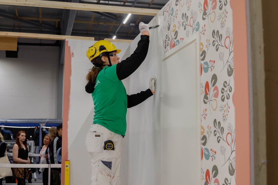 Taitaja2023 Espoo -kilpailun maalaus ja tapetointi -lajin kultamitalisti Camilla Laukkanen tapetoi seinää. Kuva: Ksenia Shurygina, Omnia / Skills Finland